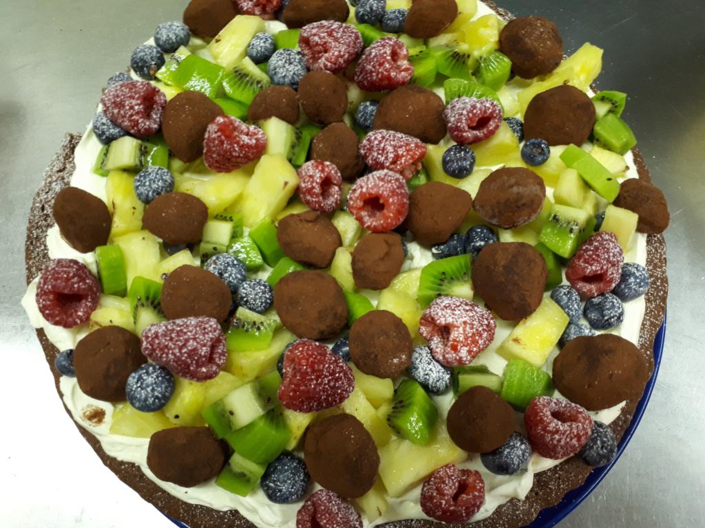 Birds eye vies of a tantalising culinary creation of chocolate cake made by James Cafe Bistro covered in Belgian truffles, pineapple, kiwis and berries