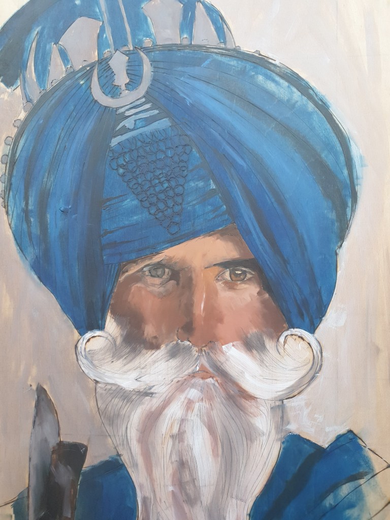 A painting of a man with a big, white beard and very distinguished curly moustache wearing a strong light blue turban and robe to match holding blade