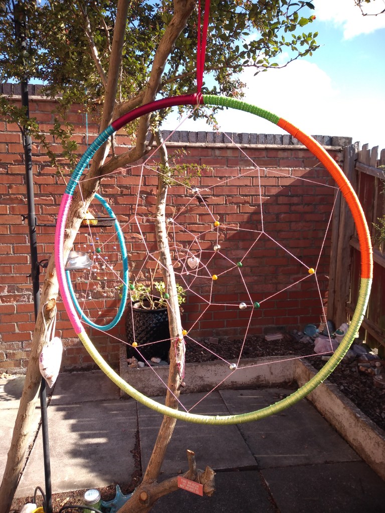Two dream catchers made by Samsdabblers using hoops and various colours of thread including pink, orange, blue, yellow and green