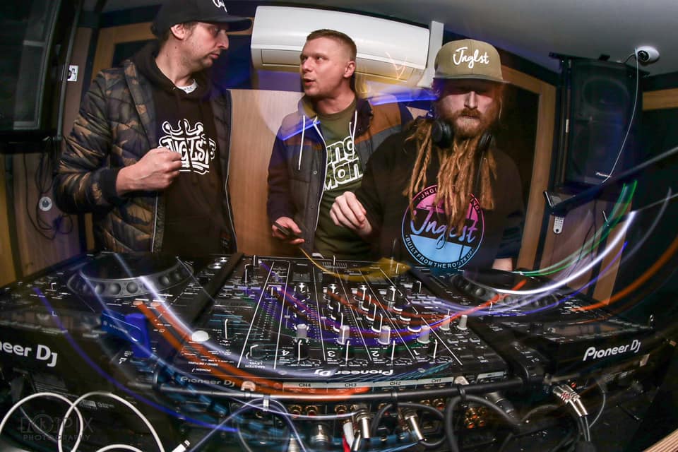 semi circular light trails in green red blue and white in front of DJs One Dread, 2 Clean and Nalin as Leicester's premier D&B crew Bass Kicks